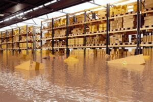 Flooded warehouse interior with water covering the floor and boxes, highlighting the need for business security and remote surveillance solutions.
