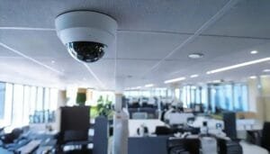 Dome security camera mounted on a ceiling in a modern office space, highlighting advanced CCTV monitoring technology. Modern office security camera providing continuous surveillance for business safety and compliance