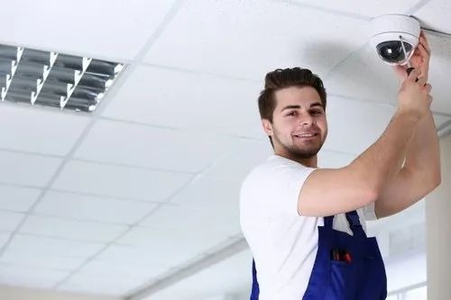 Technician installing a dome security camera on a ceiling, representing best CCTV monitoring services in Singapore.