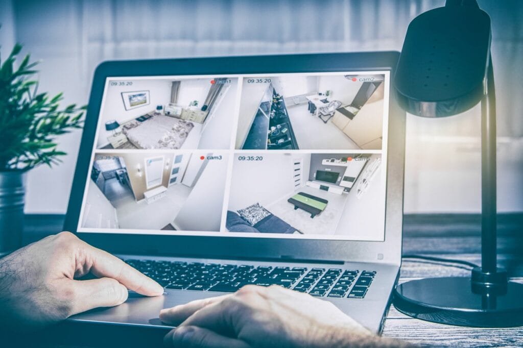 Laptop screen showing four live CCTV camera feeds of a home interior, representing remote monitoring and 24/7 CCTV monitoring services.