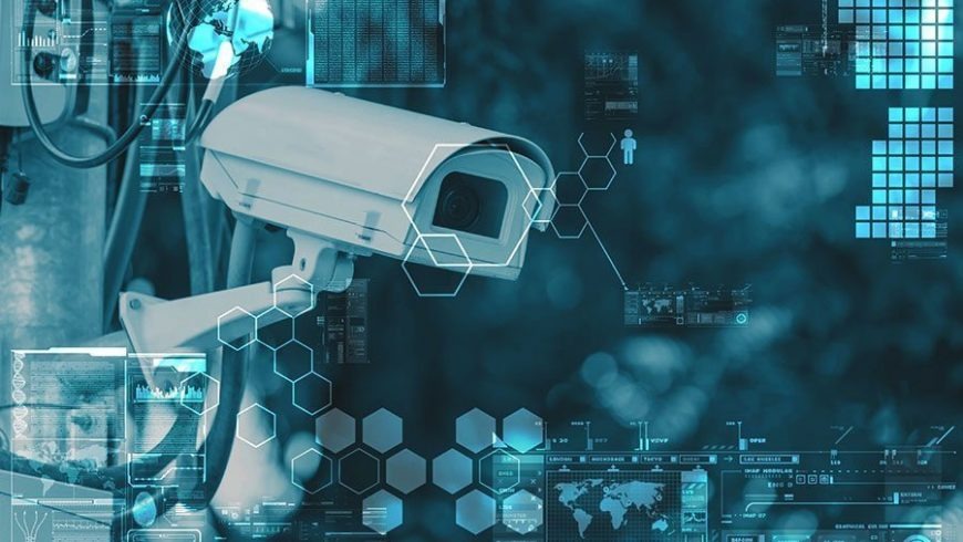 Modern bullet-style security camera against a blue tech background with data graphs and network icons, symbolizing smart video monitoring services.