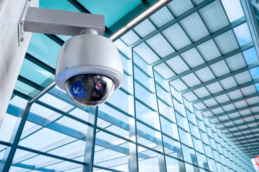 Dome security camera mounted inside a glass-walled office building, highlighting advanced CCTV monitoring for commercial spaces.