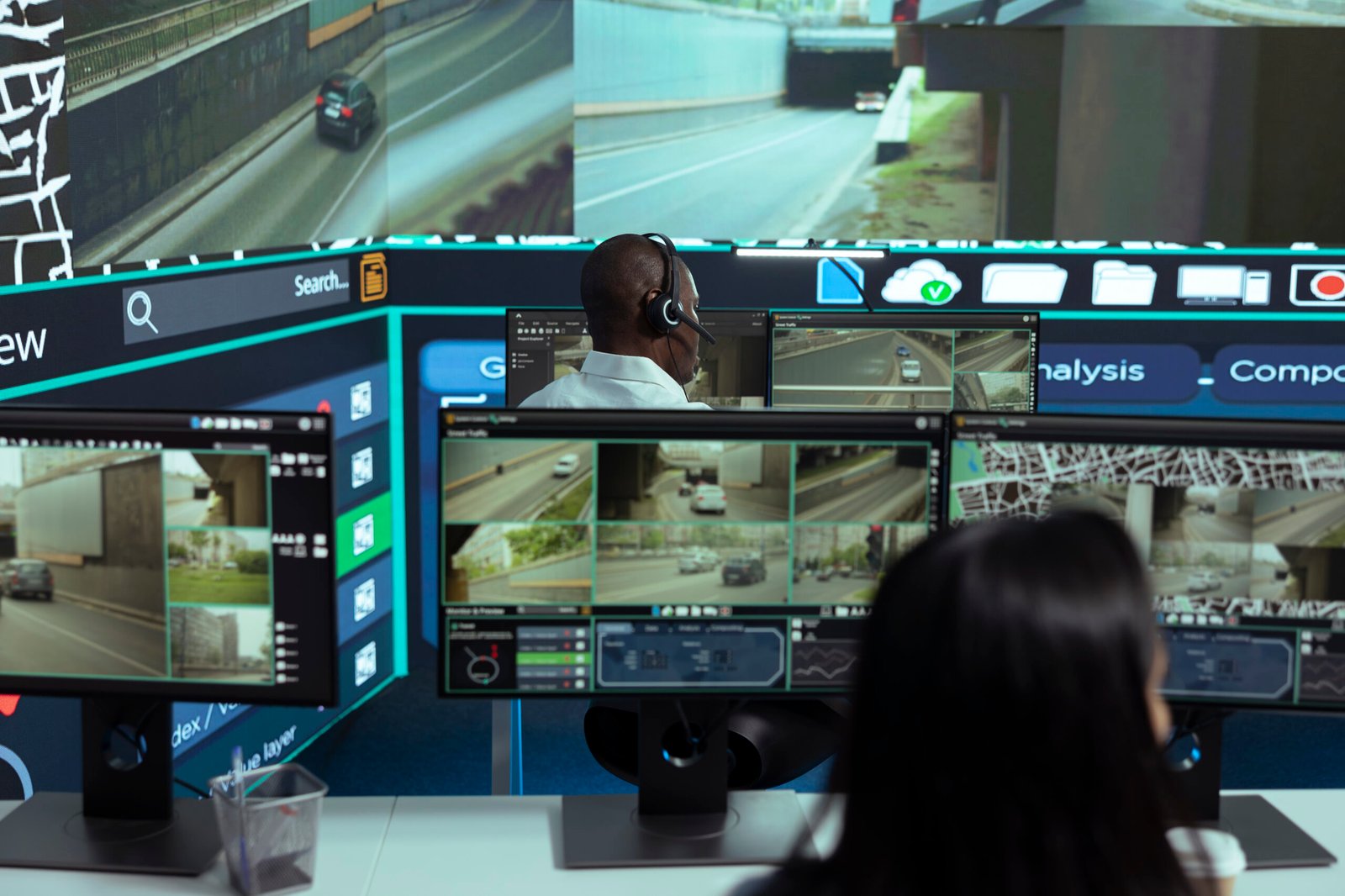Security professionals at a command center performing Live Video Monitoring on multiple screens displaying real-time traffic and road surveillance, illustrating dedicated Screen Monitoring Services.