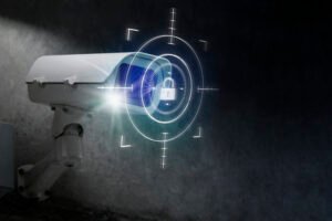 A white security camera with a glowing blue digital overlay showing a lock icon and targeting reticles, symbolizing high-tech, secure CCTV Surveillance and data protection.