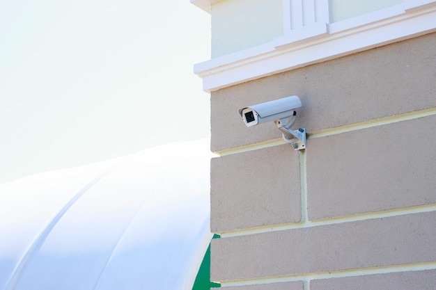 White bullet-style security camera mounted on a brick wall, symbolizing comprehensive Business Security solutions for UK businesses.