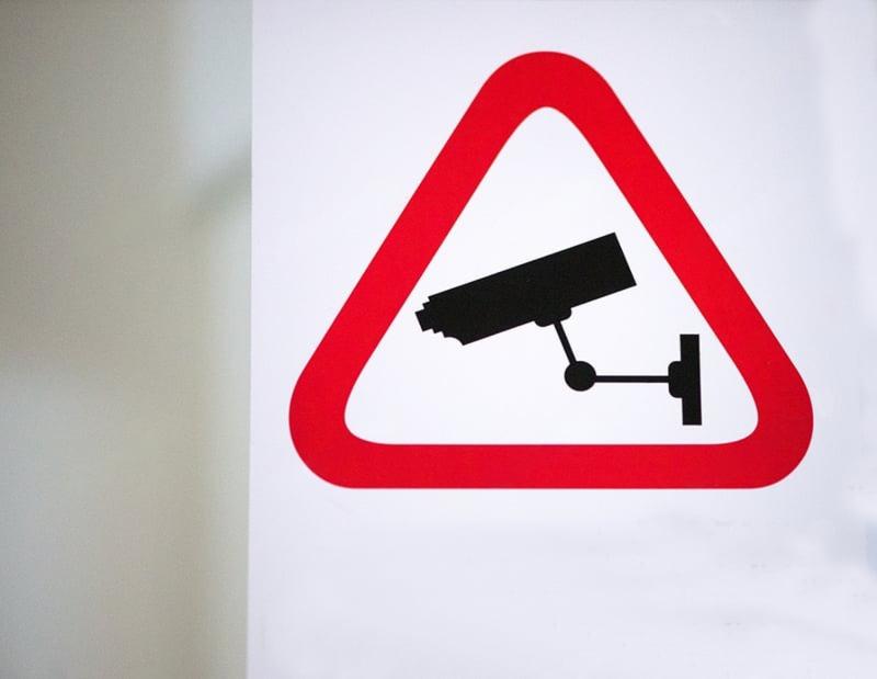 Red triangular warning sign with a black CCTV camera icon inside, promoting CCTV Monitoring.