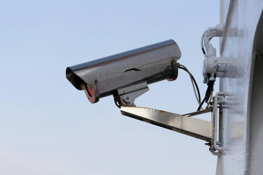 Outdoor mounted bullet-style security camera against a clear sky. A reliable component of CCTV Surveillance.
