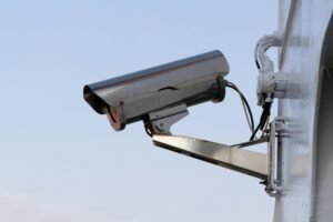 Outdoor mounted bullet-style security camera against a clear sky. A reliable component of CCTV Surveillance.