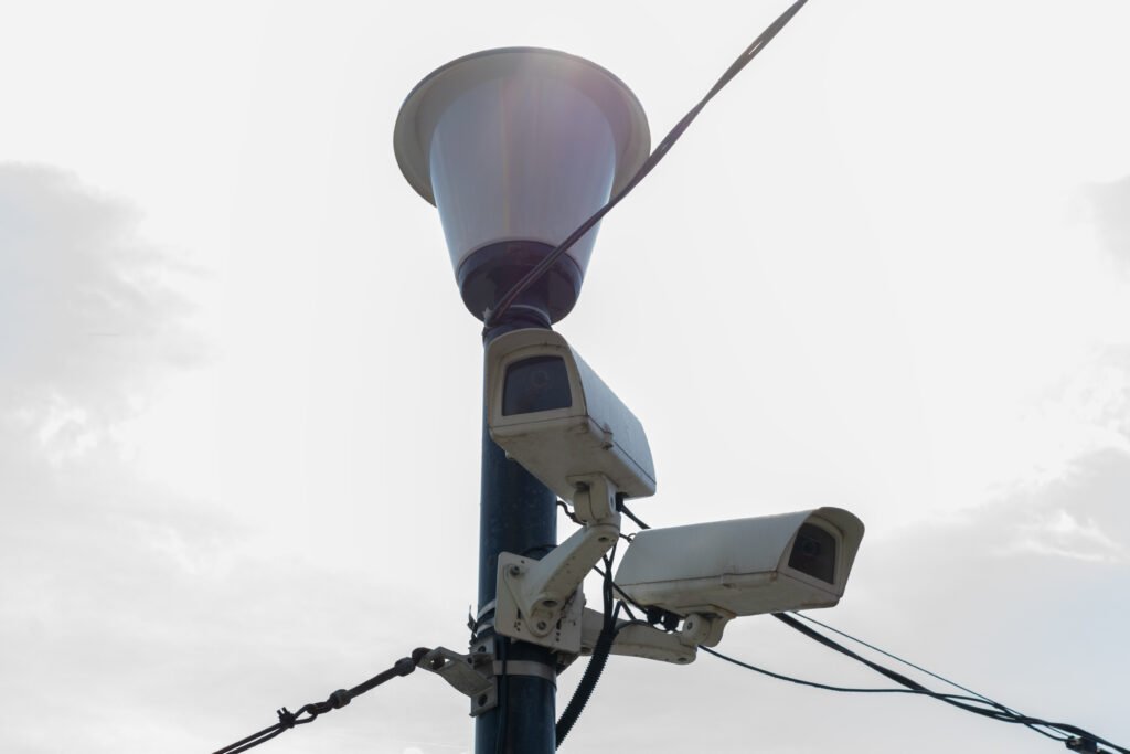 A professional security camera mounted on a fence with an orange warning beacon, demonstrating the integration of CCTV surveillance hardware with professional CCTV surveillance services