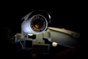A close-up view of a white commercial bullet security camera operating at night, its lens encircled by an illuminated array of infrared night-vision LEDs, showcasing the hardware layer behind automated Alarm system calls and an integrated cctv alarm system.
