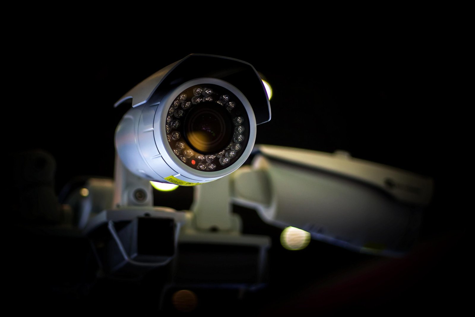 A close-up view of a white commercial bullet security camera operating at night, its lens encircled by an illuminated array of infrared night-vision LEDs, showcasing the hardware layer behind automated Alarm system calls and an integrated cctv alarm system.