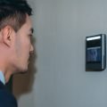 A businessman using a facial recognition wall terminal that integrates with a reliable Security Camera Monitoring Service for advanced security camera monitoring and secure live video monitoring.
