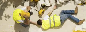 Construction worker lying on the ground after an accident, with a colleague checking on him—highlighting the need for workplace safety Singapore and incident reporting services.