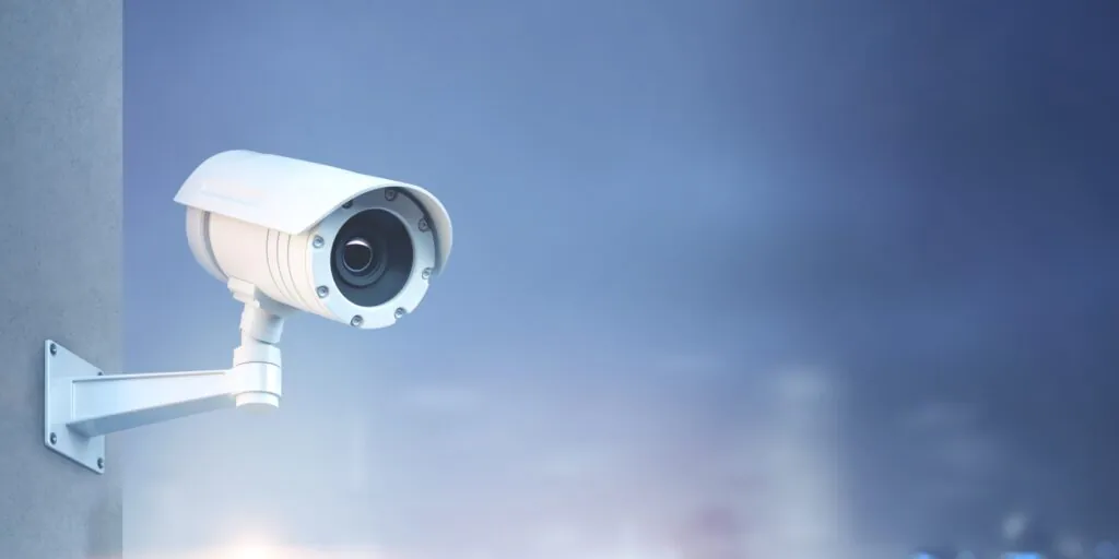 Outdoor security camera mounted on a wall, providing continuous surveillance for 24/7 live CCTV monitoring.