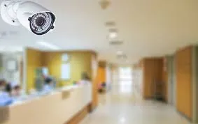 Security camera mounted on the ceiling in a hospital hallway, capturing real-time footage for live CCTV monitoring services.