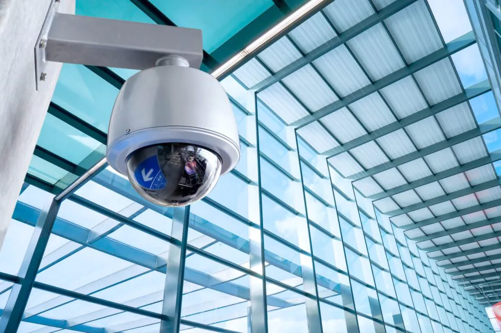 Dome security camera mounted inside a glass-walled office building, highlighting advanced CCTV monitoring for commercial spaces.