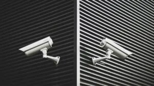Two white CCTV for Small Businesses cameras mounted on a modern building exterior with striped patterns, symbolizing reliable Small Business CCTV and professional Video Surveillance.