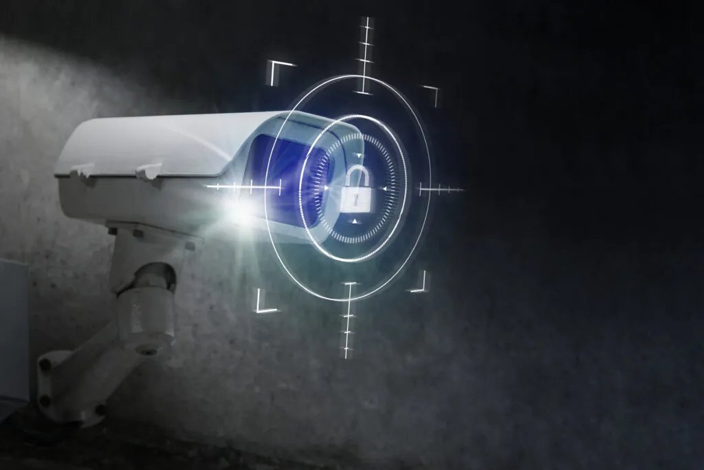 A white security camera with a glowing blue digital overlay showing a lock icon and targeting reticles, symbolizing high-tech, secure CCTV Surveillance and data protection.