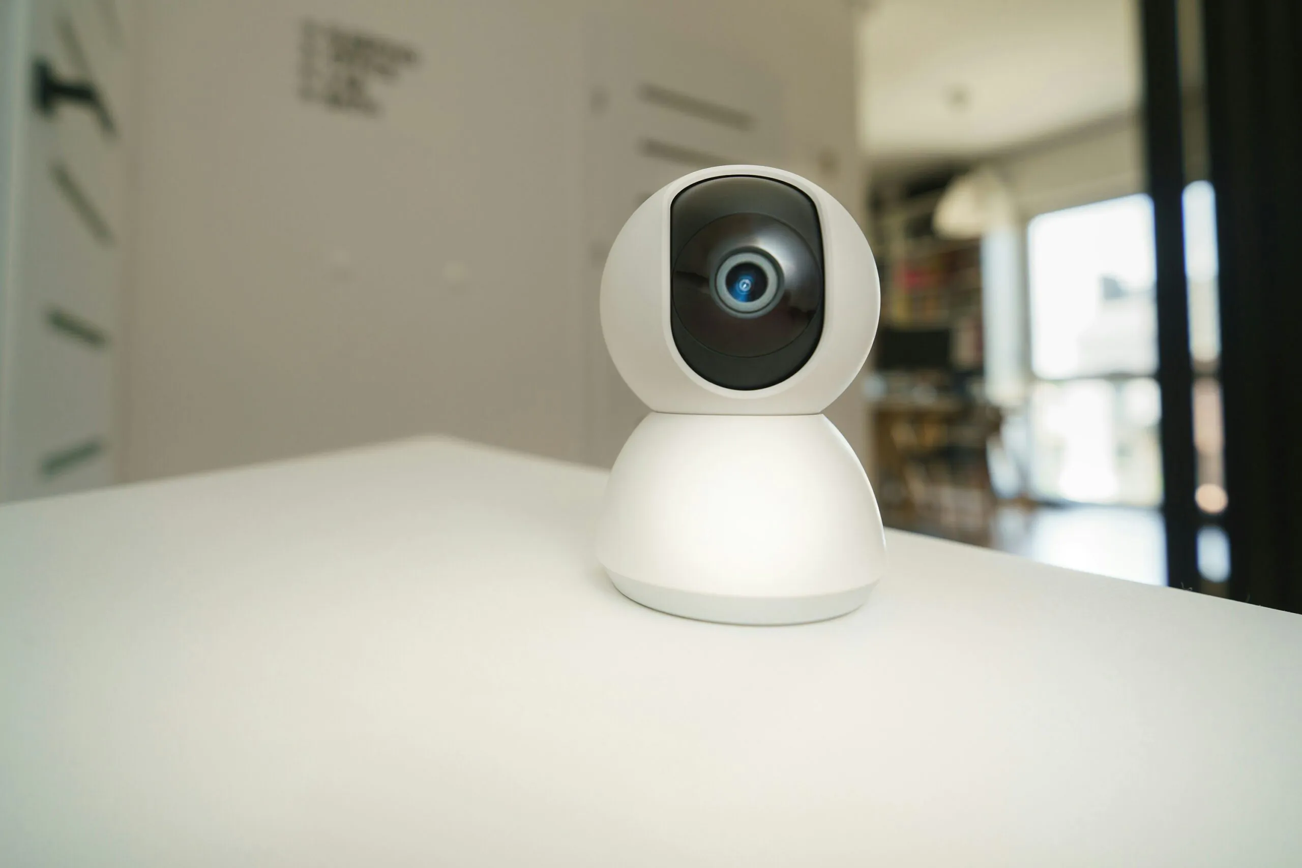 A small white indoor security camera (Nanny Cams) on a shelf in a child's room with stuffed animals, symbolizing discreet Nanny Cams Monitoring for family safety.