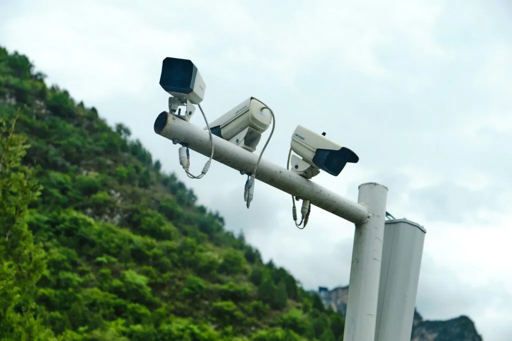 A collage of images showcasing end-to-end security, including outdoor dome cameras, indoor warehouse surveillance, multi-screen control rooms with male and female operators, access control systems, and two-way audio features, all unified by professional Remote cctv monitoring.