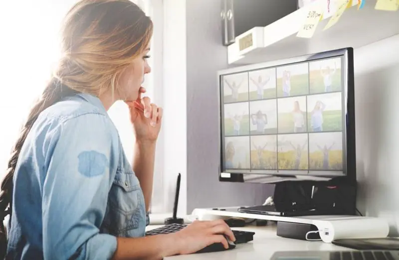 Woman monitoring a multi-pane security video feed on her desktop. Essential for effective CCTV Monitoring Services.