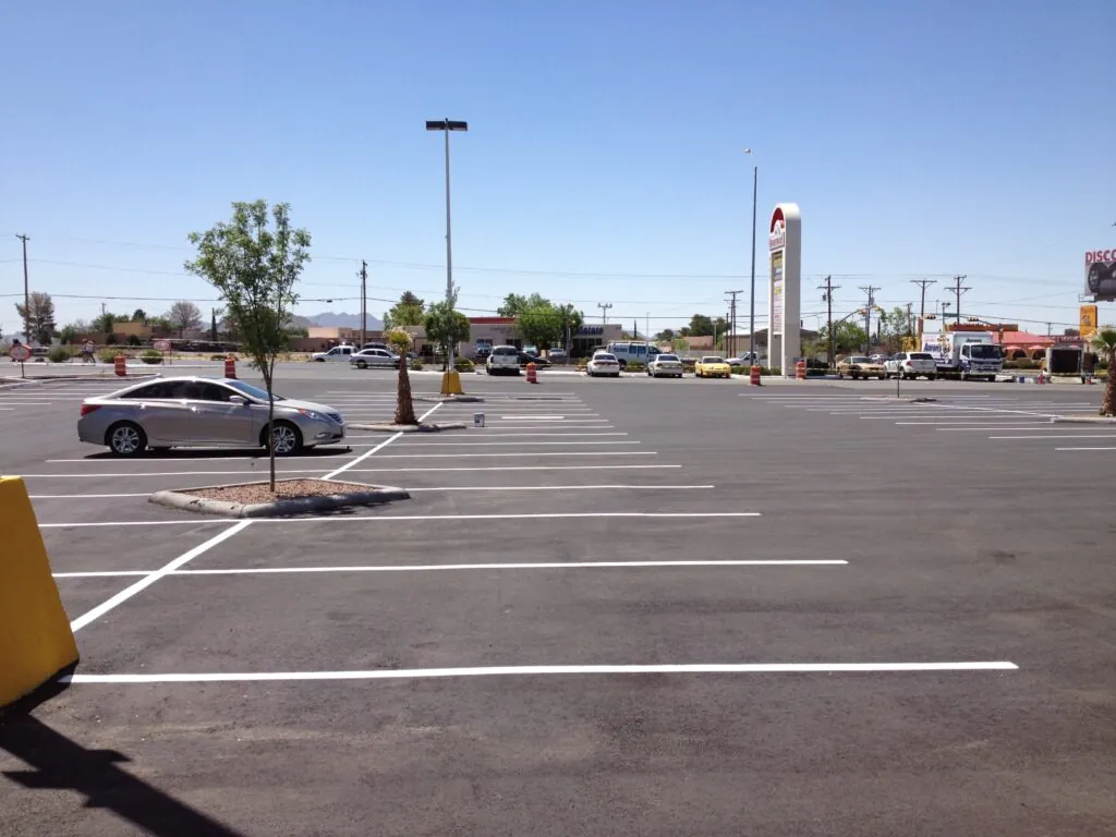 Wide, empty commercial parking lot on a sunny day. Two-way audio cameras enhance safety.