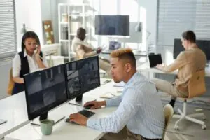 Diverse office setting with staff providing CCTV monitoring on dual screens.