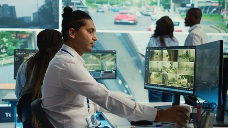 Male security operator watches multiple live feeds from various locations, demonstrating active CCTV monitoring.