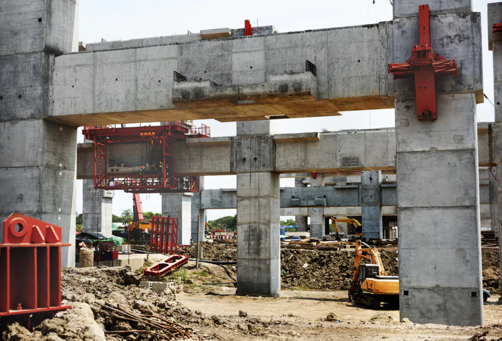 Large industrial construction site with concrete supports and heavy machinery. Requires two-way audio safety checks.