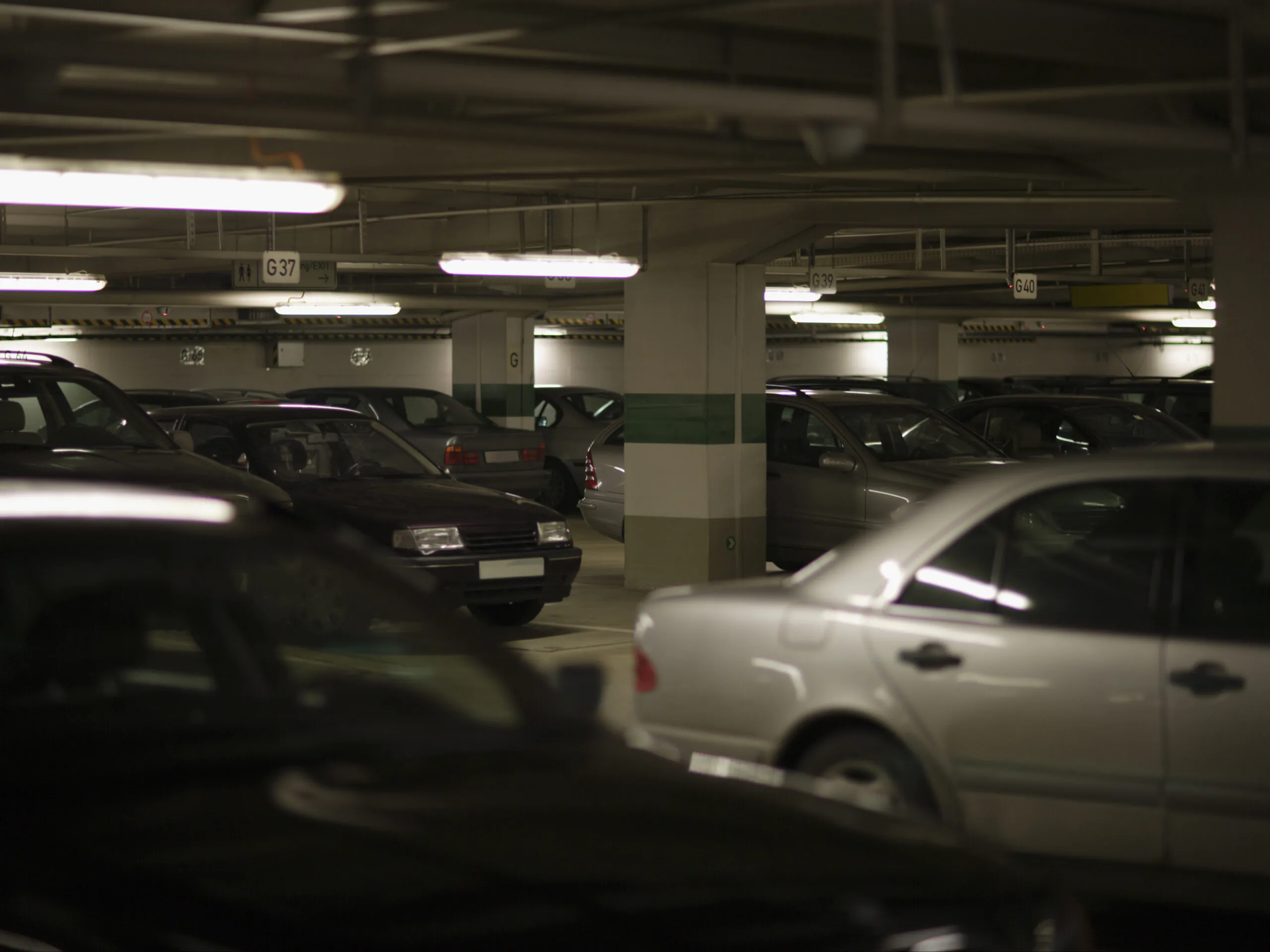 Rows of parked cars in a dimly lit indoor garage, representing a typical environment for parking lot monitoring and parking facility surveillance