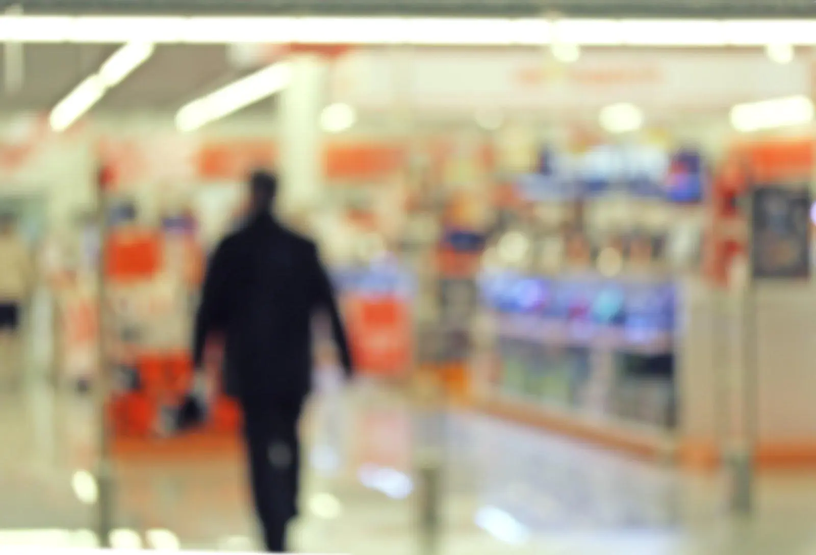 A blurred shopper walking through a retail aisle, highlighting the need for remote CCTV monitoring to ensure retail theft prevention.