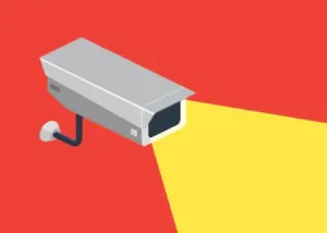 An isometric illustration of a grey security camera emitting a bright yellow cone of light against a red background, symbolizing active Camera Monitoring and professional Camera Monitoring Services for crime prevention