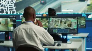 A professional security operator in a control room performing Remote CCTV Monitoring and Security Monitoring across multiple video feeds