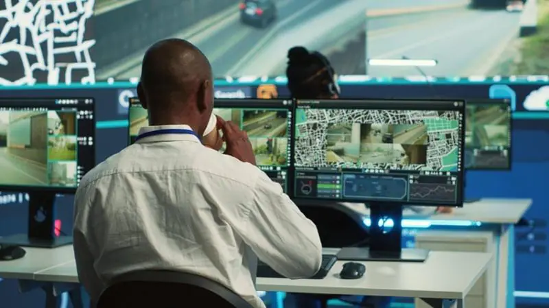 A professional security operator in a control room performing Remote CCTV Monitoring and Security Monitoring across multiple video feeds