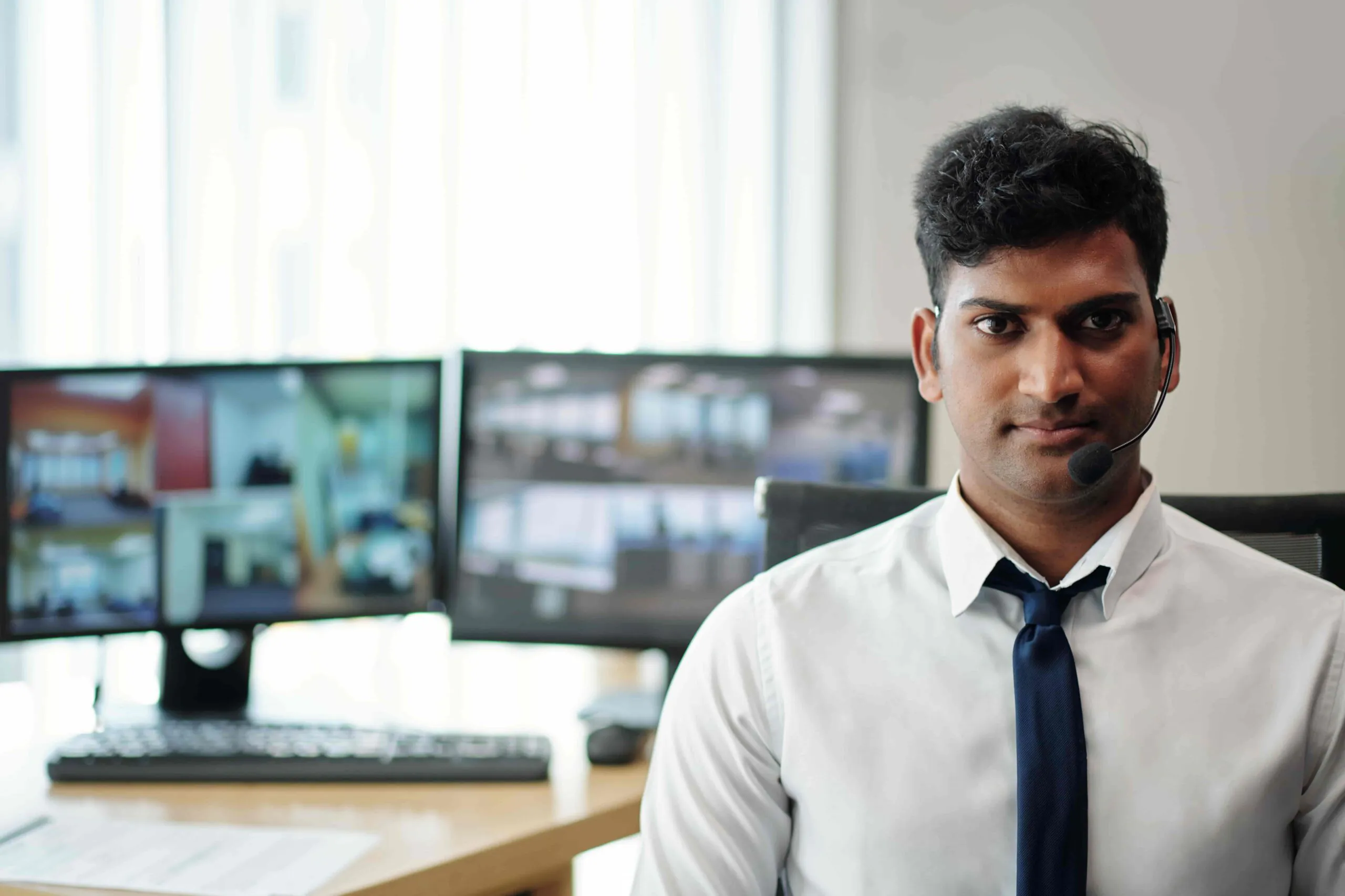 A professional operator with a headset sitting at a desk with monitors, representing the execution of Virtual Doorman Responsibilities and standard Doorman Responsibilities using modern CCTV Access Control.