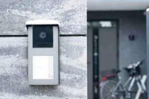 A close-up of a sleek video intercom system mounted on a snowy stone wall, functioning as a high-tech Apartment Doorman for enhanced Building Security at a modern Apartment.