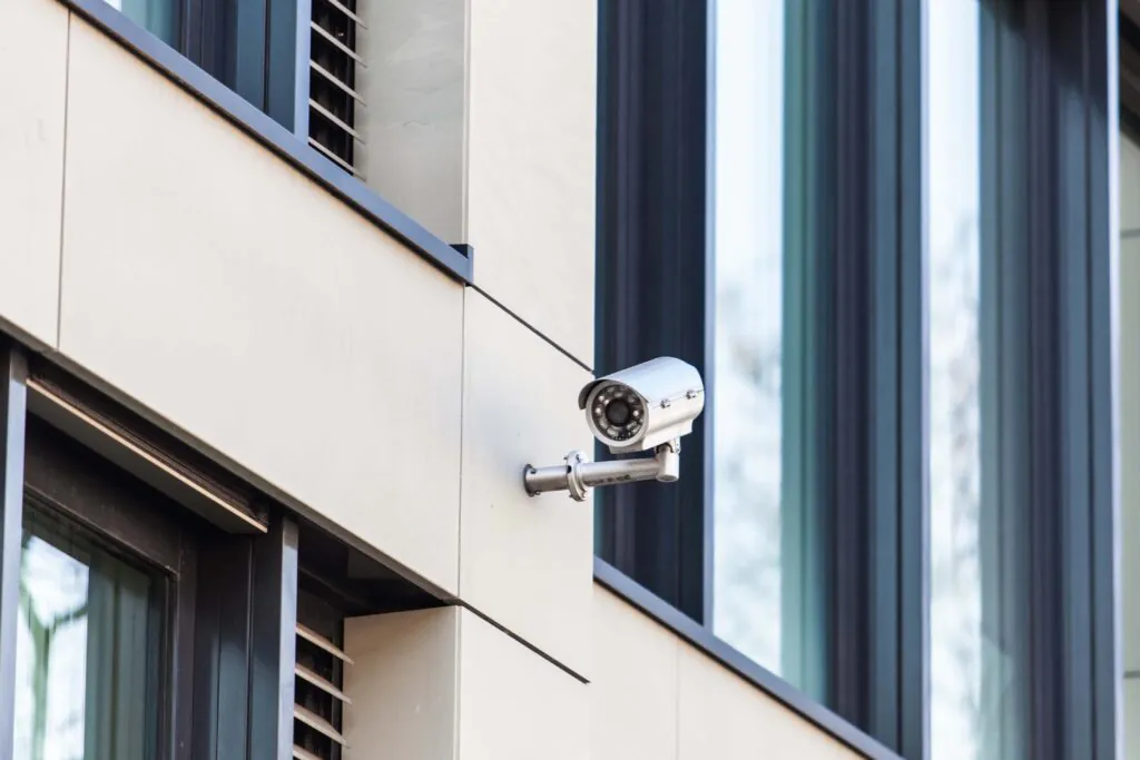 A bullet-style security camera mounted on the modern exterior facade of an educational facility, demonstrating the durable hardware required for effective CCTV Monitoring for Schools and proactive surveillance monitoring.