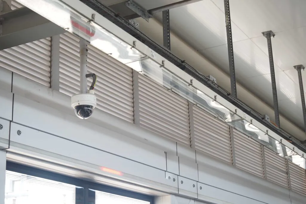 A professional dome security camera mounted securely to the high ceiling of an industrial facility, representing the durable hardware required for effective CCTV monitoring for warehouses and comprehensive commercial video surveillance.